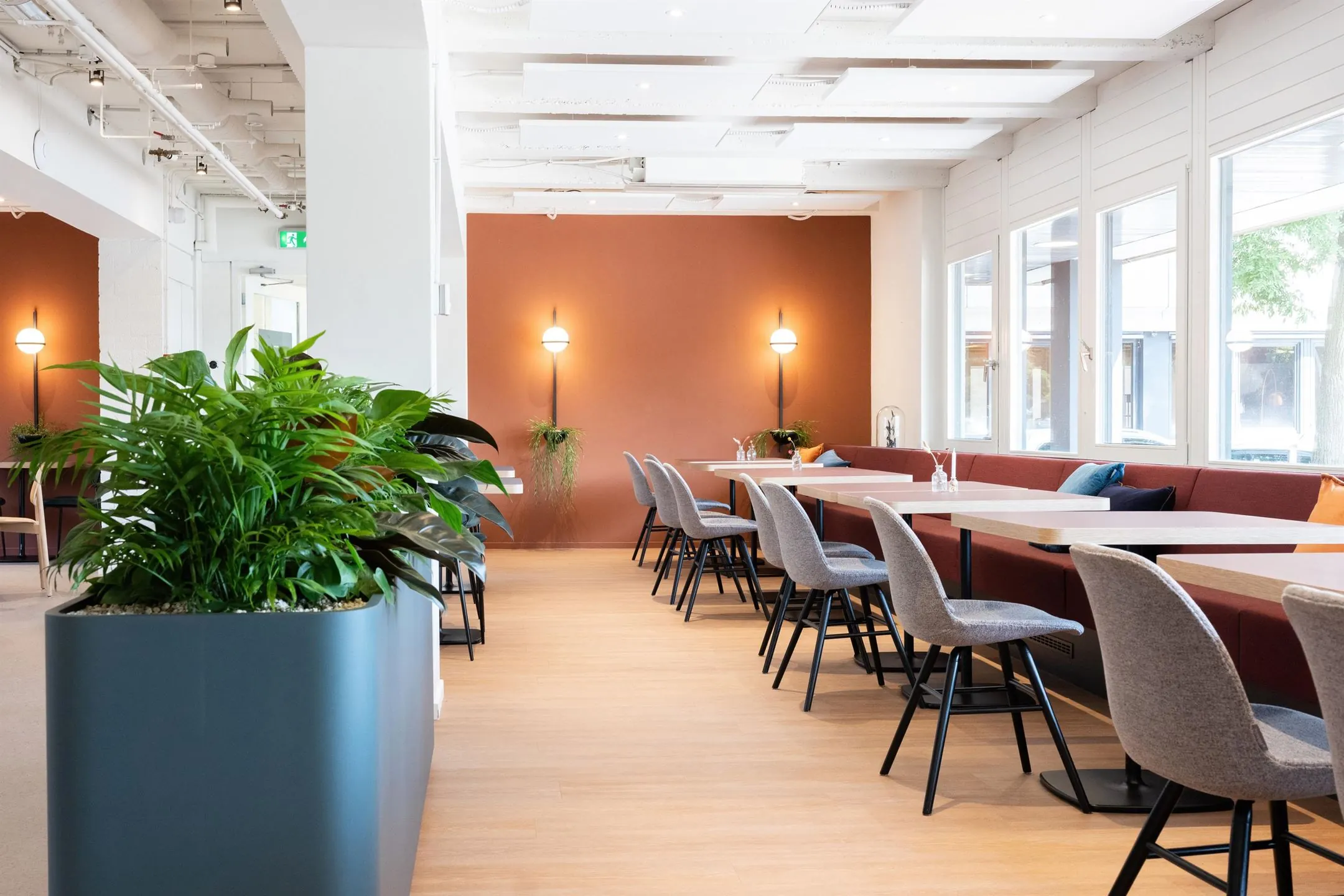 Moderne kantoorruimte met lange werktafels, grijze stoelen, planten en grote ramen aan de Atoomweg 50 in Utrecht.