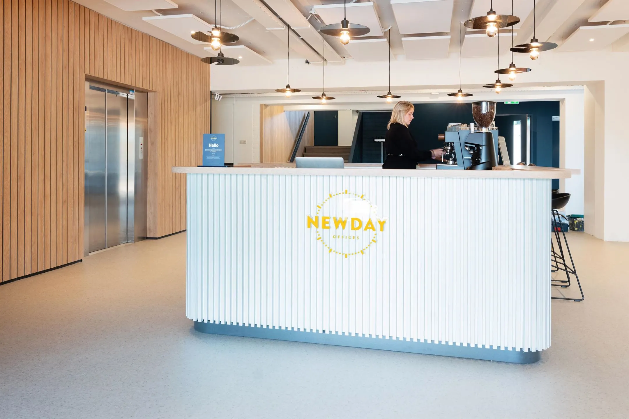Moderne receptiebalie van NewDay Offices met een koffiemachine en een medewerker, gelegen aan de Atoomweg 50 in Utrecht.