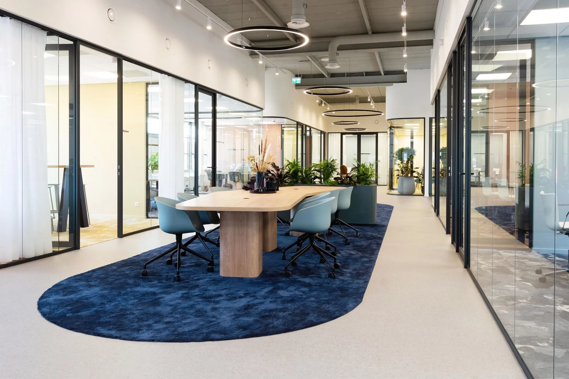 Moderne kantoorruimte met glazen vergaderruimtes, een houten vergadertafel en blauwe accenten aan de Atoomweg 50 in Utrecht.