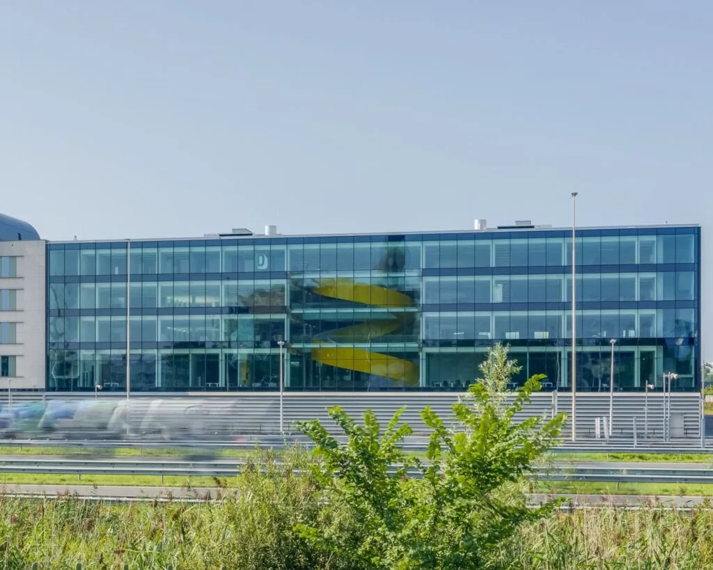 Modern glazen kantoorgebouw aan de Reykjavikstraat in Utrecht met opvallende gele wenteltrap binnenin.