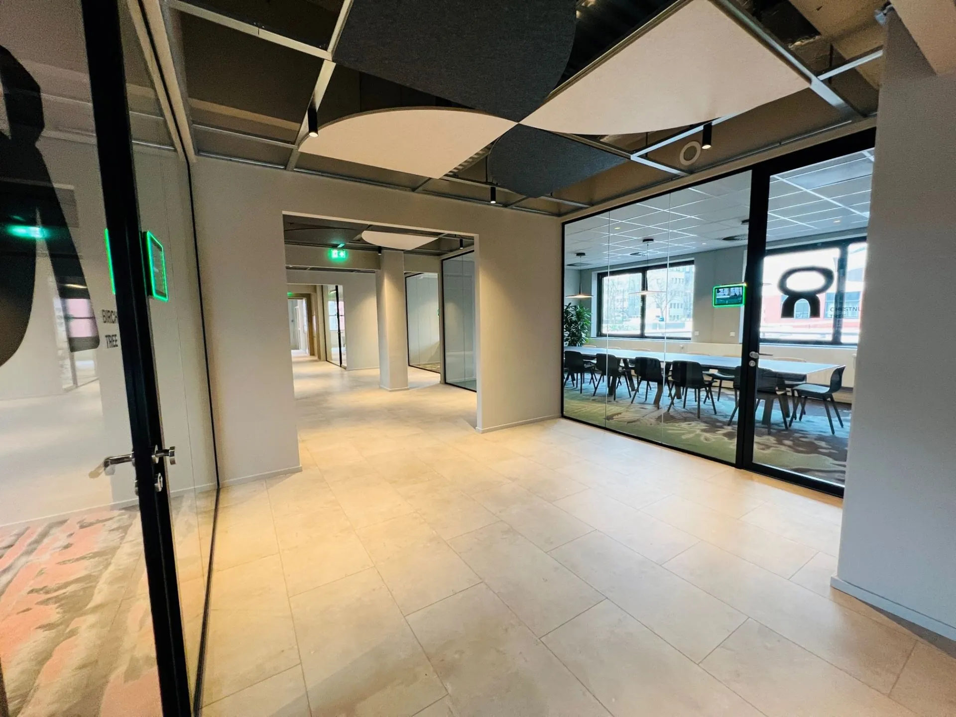 Moderne gang in een kantoorpand met glazen wanden en vergaderruimte aan de Varrolaan 100 in Utrecht.