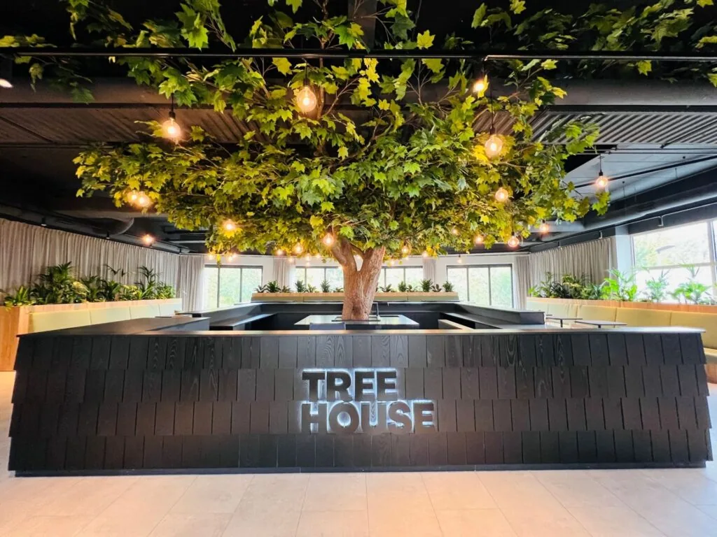 Moderne kantoorruimte in Utrecht met centraal geplaatste kunstboom en het verlichte logo "Tree House".