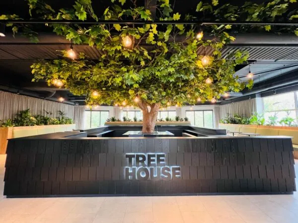 Moderne kantoorruimte in Utrecht met centraal geplaatste kunstboom en het verlichte logo "Tree House".