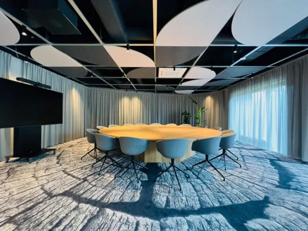 Moderne vergaderruimte met ronde houten tafel en designstoelen in kantoor aan de Varrolaan 100 in Utrecht.
