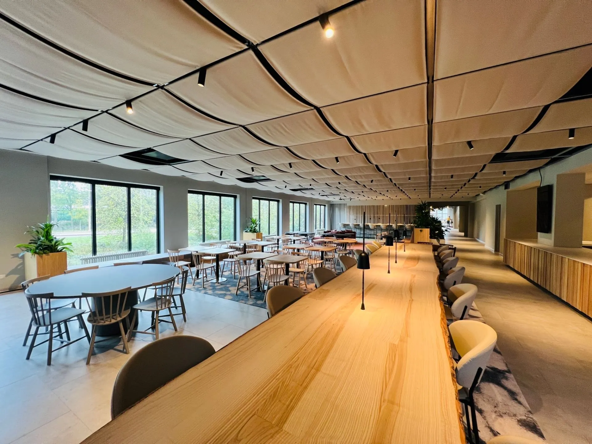 Moderne, lichte kantoorruimte met lange houten werktafels en zithoeken aan de Varrolaan 100 in Utrecht.