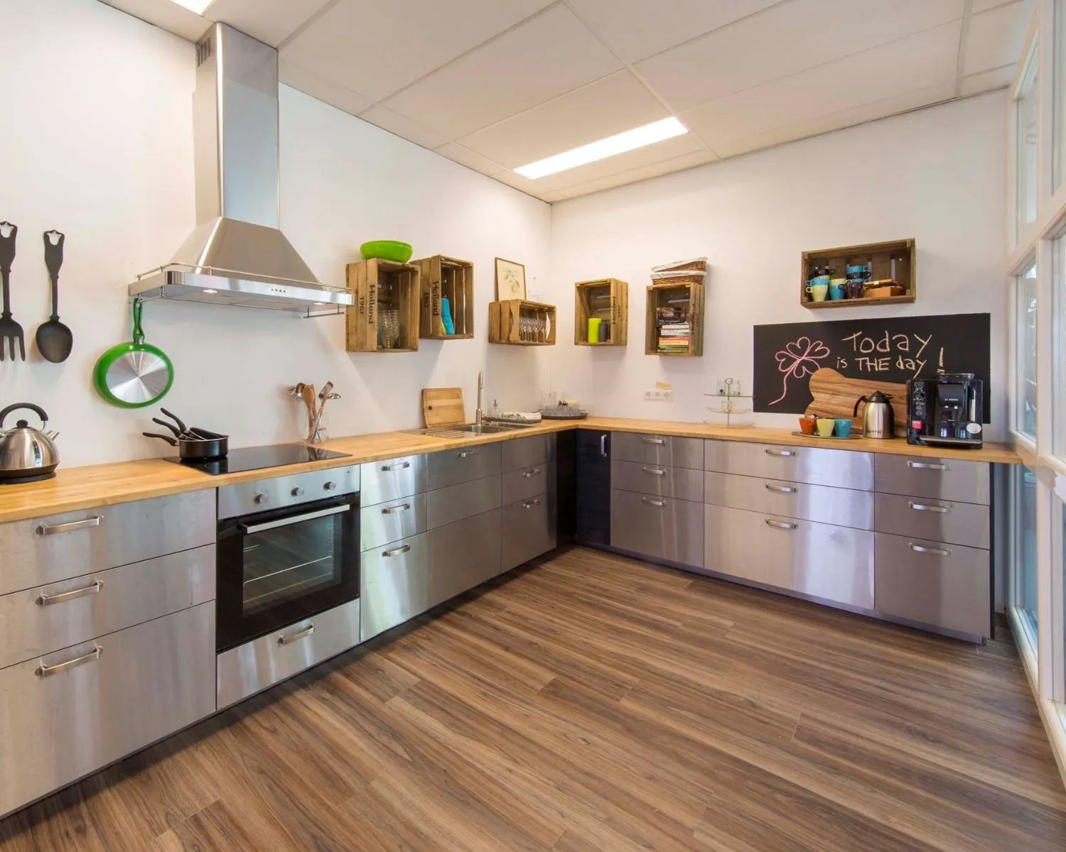 Moderne kantoorkeuken aan de Waarderweg 19-6 met rvs-kasten, houten werkblad en een krijtbord met de tekst "Today is THE day".