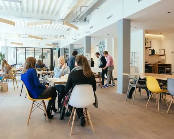 Moderne gedeelde kantoorruimte aan de Weteringschans 165 met mensen die werken en overleggen aan tafels.