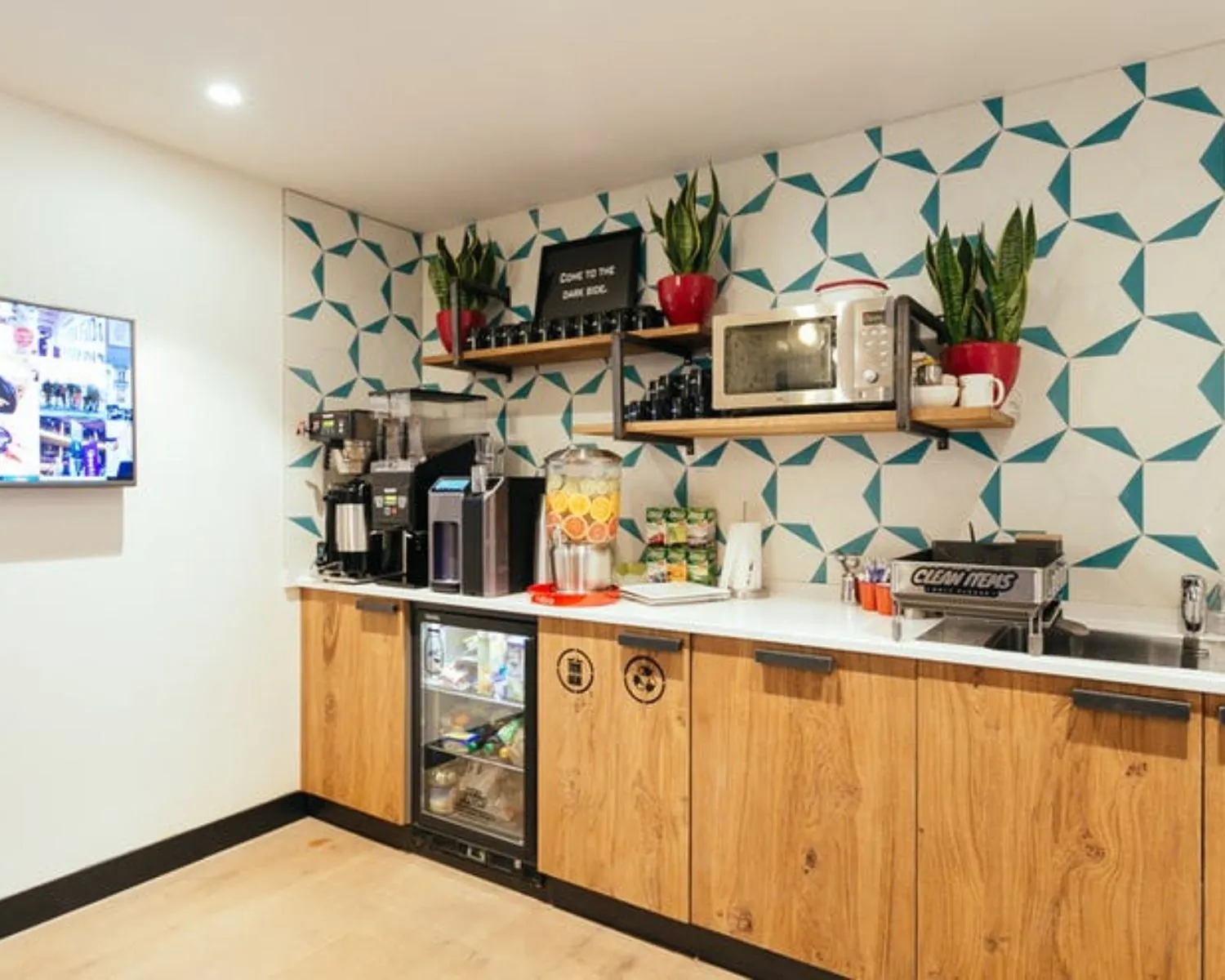 Moderne pantry in kantoorruimte aan de Weteringschans 165 met koffieapparaten, magnetron, drankdispenser en houten keukenkastjes.