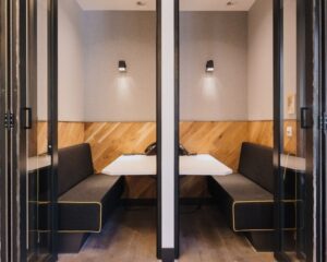 Moderne kantoorruimte met twee aparte werkpods voorzien van houten wanden, zwarte banken en witte tafels aan de Weteringschans 165.