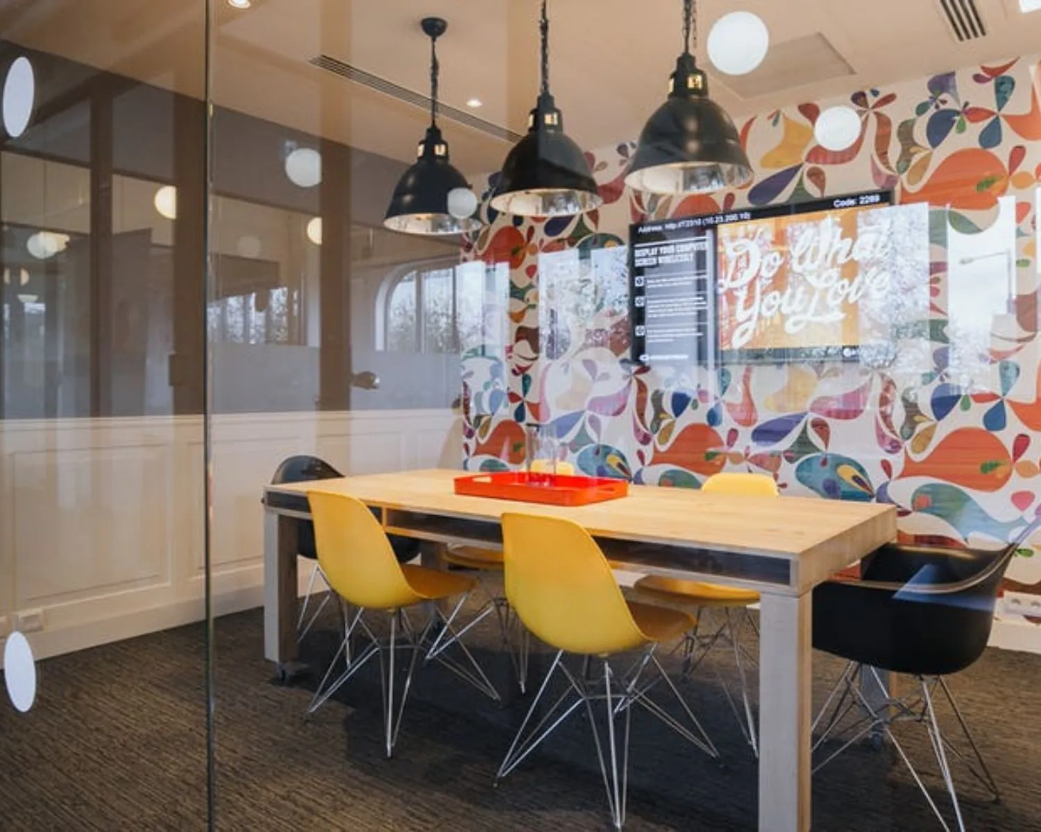 Moderne vergaderruimte op Weteringschans 165 met kleurrijke wand, houten tafel, designstoelen en glazen wanden.