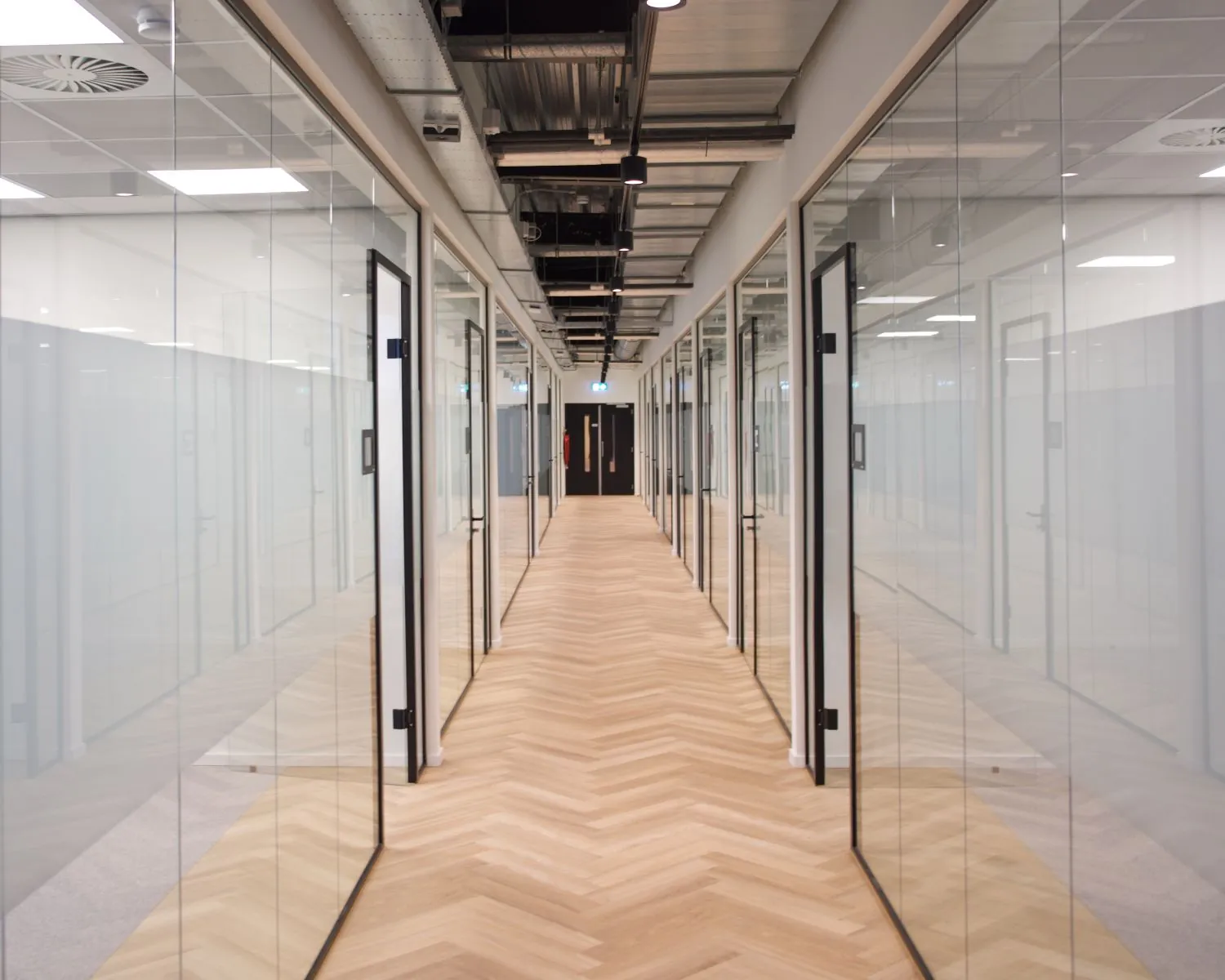 Moderne kantoorruimte met glazen kantoormuren en houten visgraatvloer aan het Bos en Lommerplein.