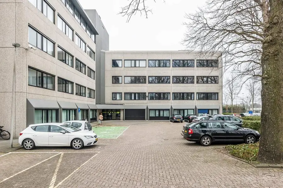 Vooraanzicht van het kantoorgebouw aan de Heerbaan 14 in Breda met parkeerplaatsen op de voorgrond.