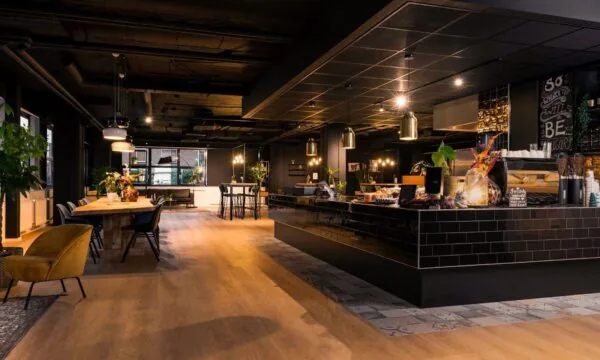 Moderne kantoorruimte aan de Heerbaan 14 in Breda met stijlvolle inrichting, houten vloeren en een sfeervolle koffiebar.