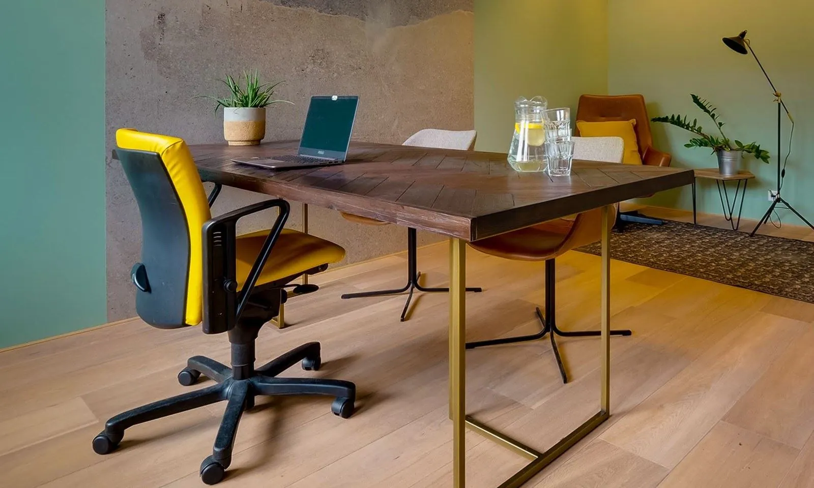 Moderne kantoorruimte in Breda met houten vloer, stijlvol bureau, gele bureaustoel en sfeervolle inrichting.