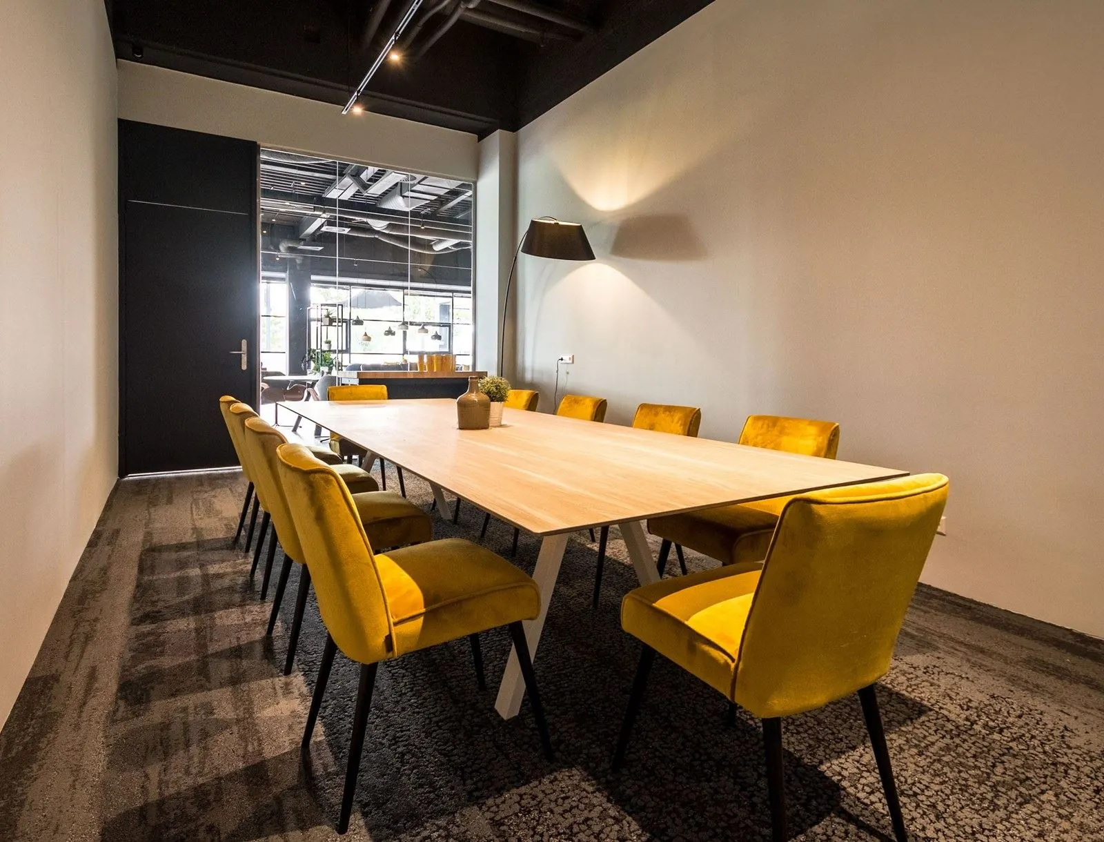 Vergaderruimte met lange houten tafel en gele stoelen in kantoorruimte aan de Heerbaan 14 in Breda.