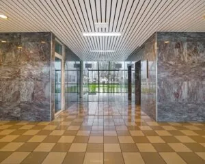 Ingangshal van een kantoorruimte aan de Haagse Schouwweg met marmeren wanden en grote ramen aan het einde van de gang.