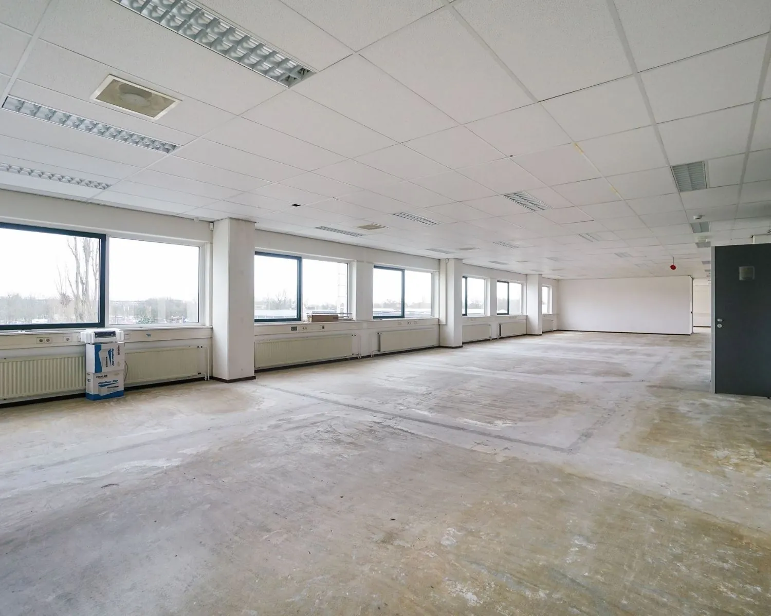 Lege kantoorruimte met systeemplafond en grote ramen aan de Haagse Schouwweg 8-7.