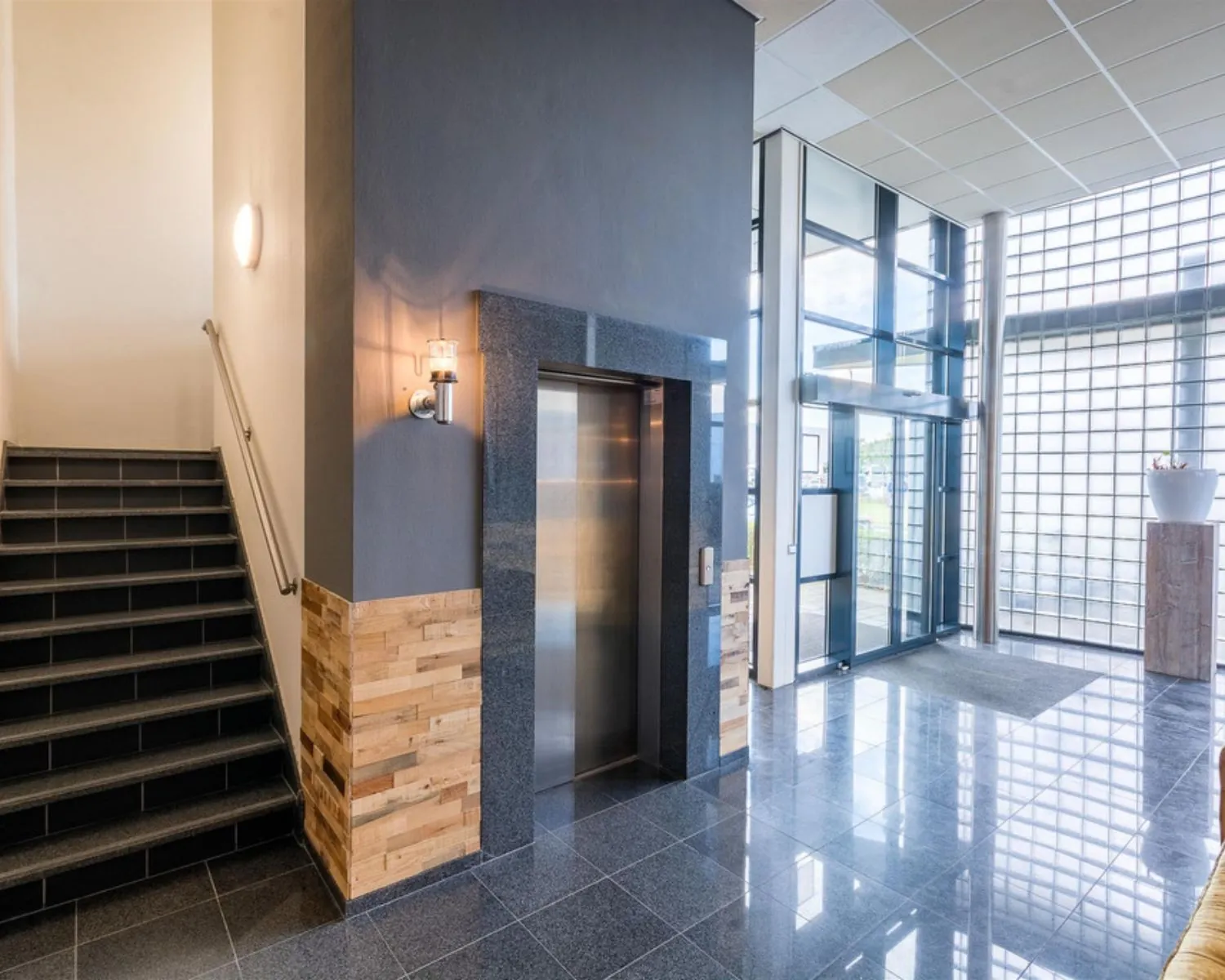 Moderne entreehal van een kantoorpand aan de Mollerusweg 84 met lift, trap en glazen gevel.