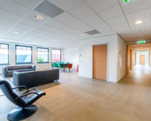 Moderne en lichte kantoorruimte aan de Mollerusweg 84 met zitgedeelte, vergadertafel en lange gang.