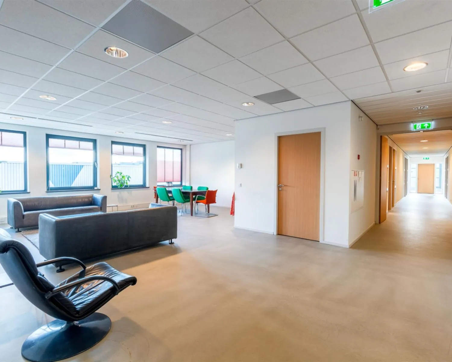 Moderne en lichte kantoorruimte aan de Mollerusweg 84 met zitgedeelte, vergadertafel en lange gang.