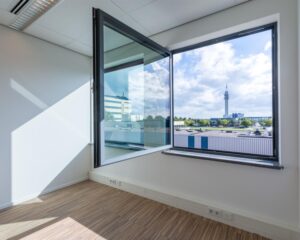 Lichte, moderne kantoorruimte aan de Mollerusweg 84 met groot open raam en uitzicht op bedrijventerrein.