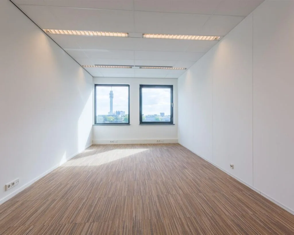 Lichte, rechthoekige kantoorruimte met tapijtvloer en twee ramen aan de Mollerusweg 84.
