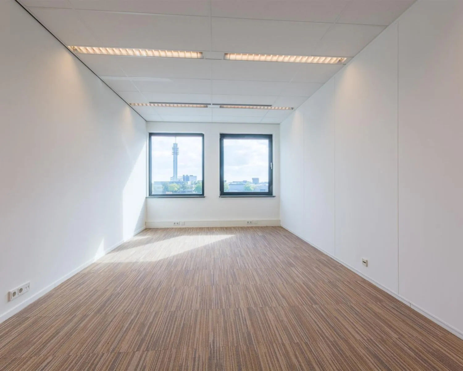 Lichte, rechthoekige kantoorruimte met tapijtvloer en twee ramen aan de Mollerusweg 84.