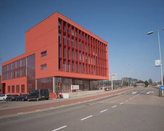 Modern rood kantoorgebouw aan de Panamalaan met grote ramen en parkeergelegenheid aan de voorzijde.