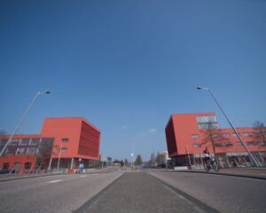 Twee rode kantoorgebouwen aan de Panamalaan in Amsterdam met een lege weg en een fietser op de voorgrond.