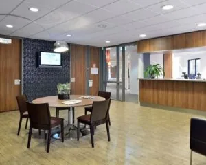 Moderne kantoorruimte aan de Pascalstraat 15 met houten receptiebalie, ronde vergadertafel en stijlvolle inrichting.