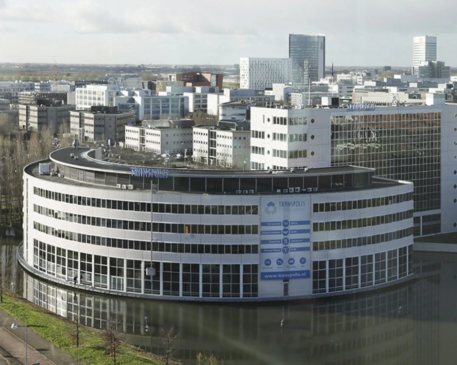 Kantoorgebouw Transpolis aan de Polarisavenue 1 in Hoofddorp met omliggende kantoorpanden en waterpartij op de voorgrond.