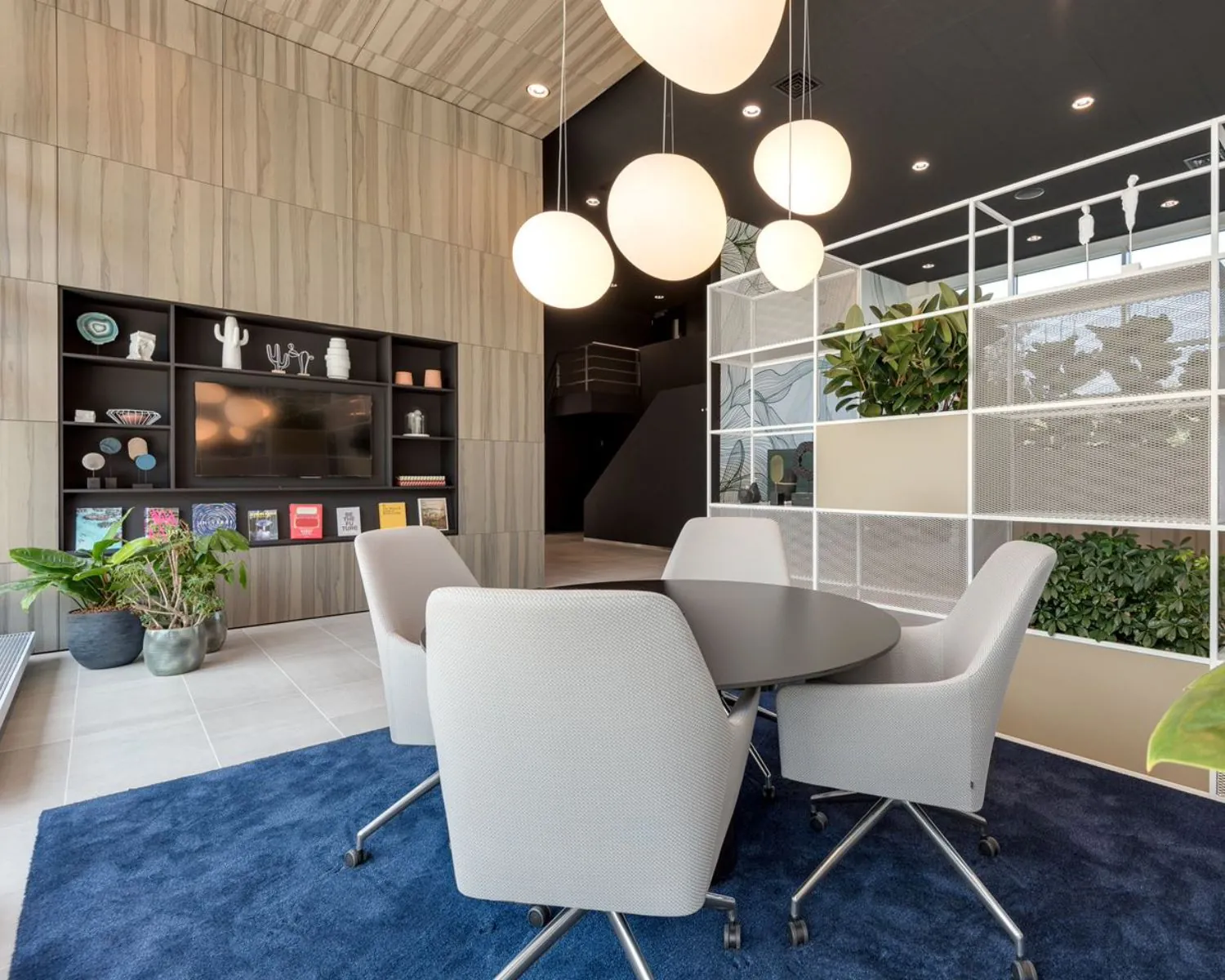 Moderne kantoorruimte aan de Polarisavenue 1 in Hoofddorp met ronde vergadertafel, designstoelen, plantenwand en sfeervolle verlichting.