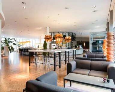 Moderne, open kantoorruimte met zithoeken, een bar en opvallende oranje hanglampen aan de Polarisavenue 1 in Hoofddorp.