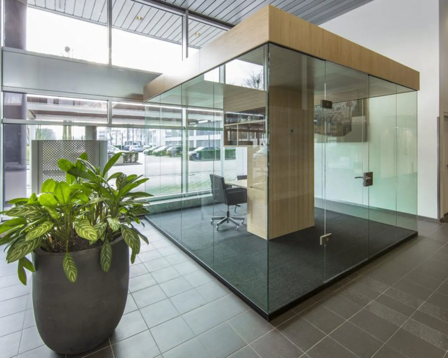 Moderne glazen vergaderruimte in een kantoorruimte aan de Polarisavenue 1 in Hoofddorp met een grote plant op de voorgrond.
