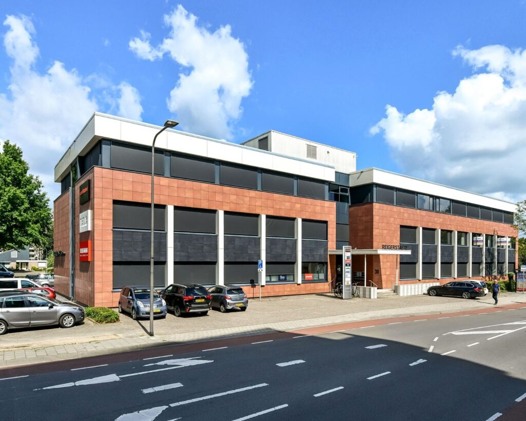 Moderne kantoorruimte aan de Reigerstraat 30 met rode gevel, grote ramen en parkeergelegenheid voor de deur.