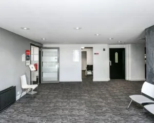 Moderne entreehal van kantoorruimte aan de Reigerstraat 30 met grijze vloerbedekking en wachtruimte.