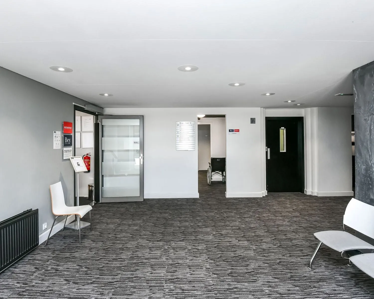 Moderne entreehal van kantoorruimte aan de Reigerstraat 30 met grijze vloerbedekking en wachtruimte.