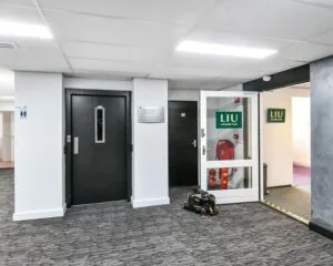 Entree van een kantoorruimte aan de Reigerstraat 30 met liftdeur, bewegwijzering en ingang naar LIU Acupunctuur.