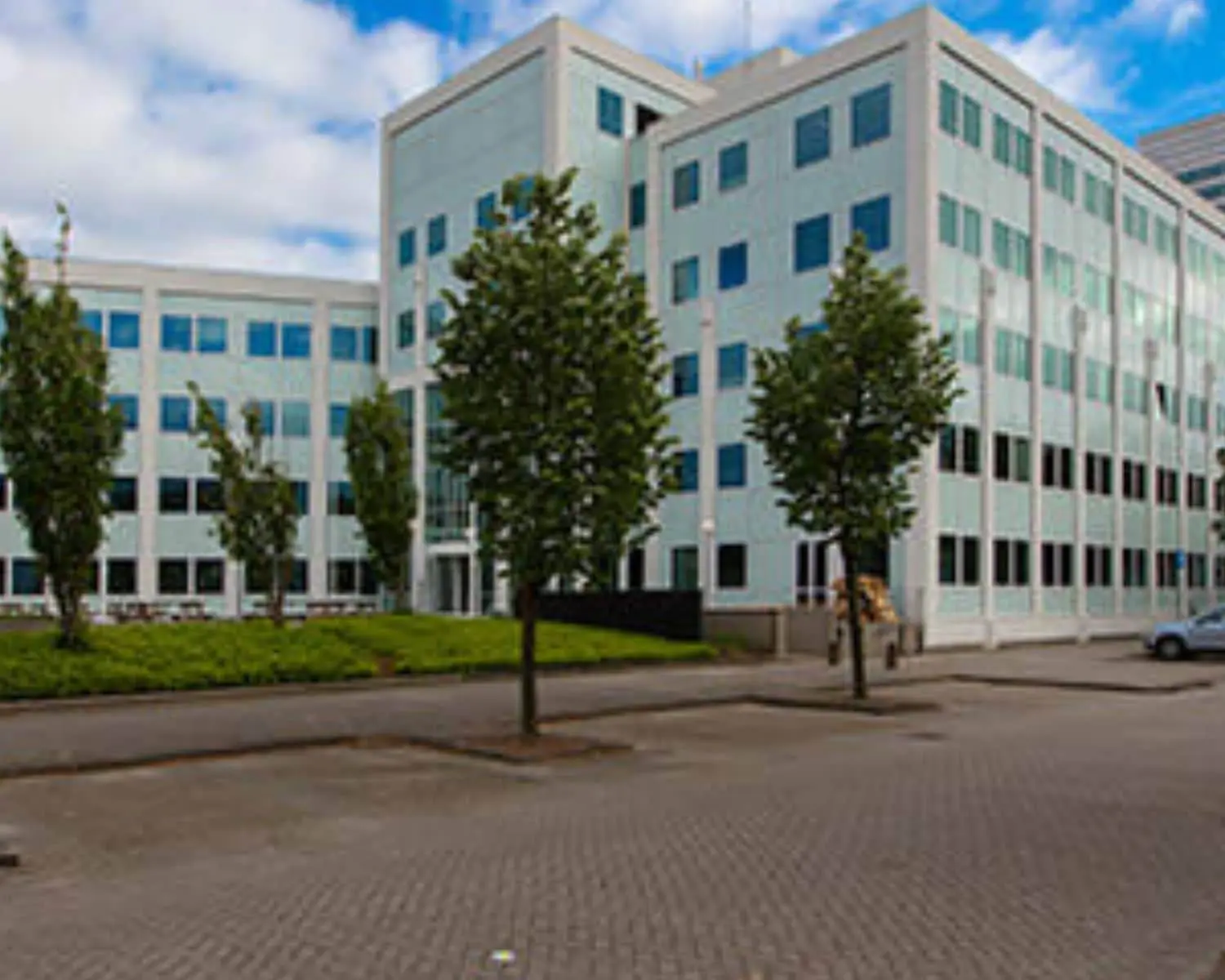 Kantoorgebouw aan de Saturnusstraat 46 in Hoofddorp met parkeerplaatsen en jonge bomen op de voorgrond.