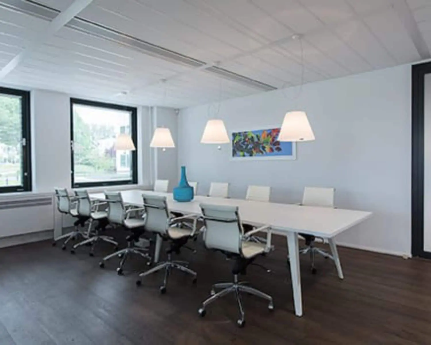 Moderne vergaderruimte met lange witte tafel, designstoelen en hanglampen aan de Saturnusstraat 46 in Hoofddorp.