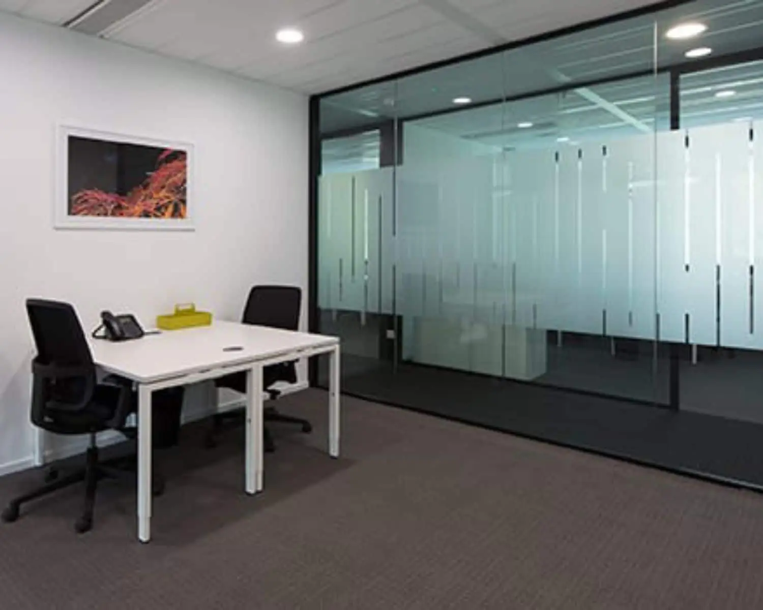 Moderne kantoorruimte met twee bureaustoelen, een wit bureau en glazen scheidingswand aan de Saturnusstraat 46 in Hoofddorp.