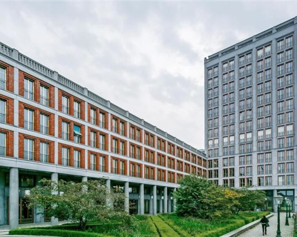 Moderne kantoorgebouwen met grote ramen aan het Stationsplein 8-10, omgeven door een groene binnentuin.