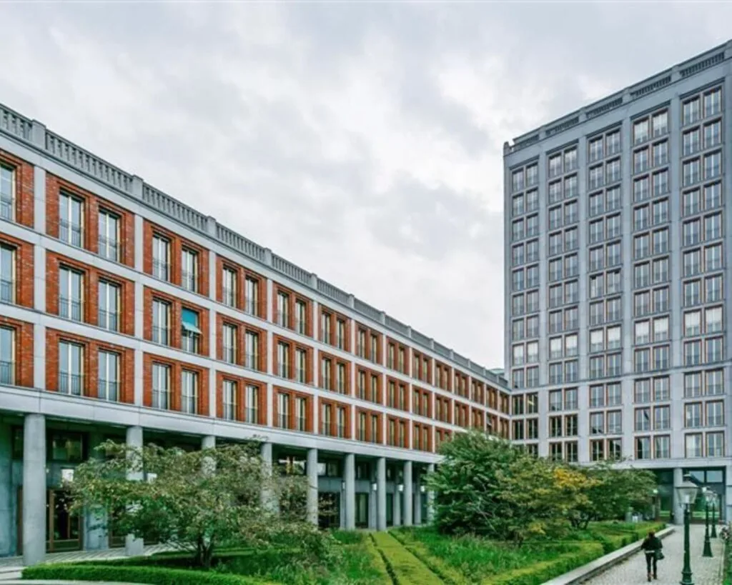 Moderne kantoorgebouwen met grote ramen aan het Stationsplein 8-10, omgeven door een groene binnentuin.