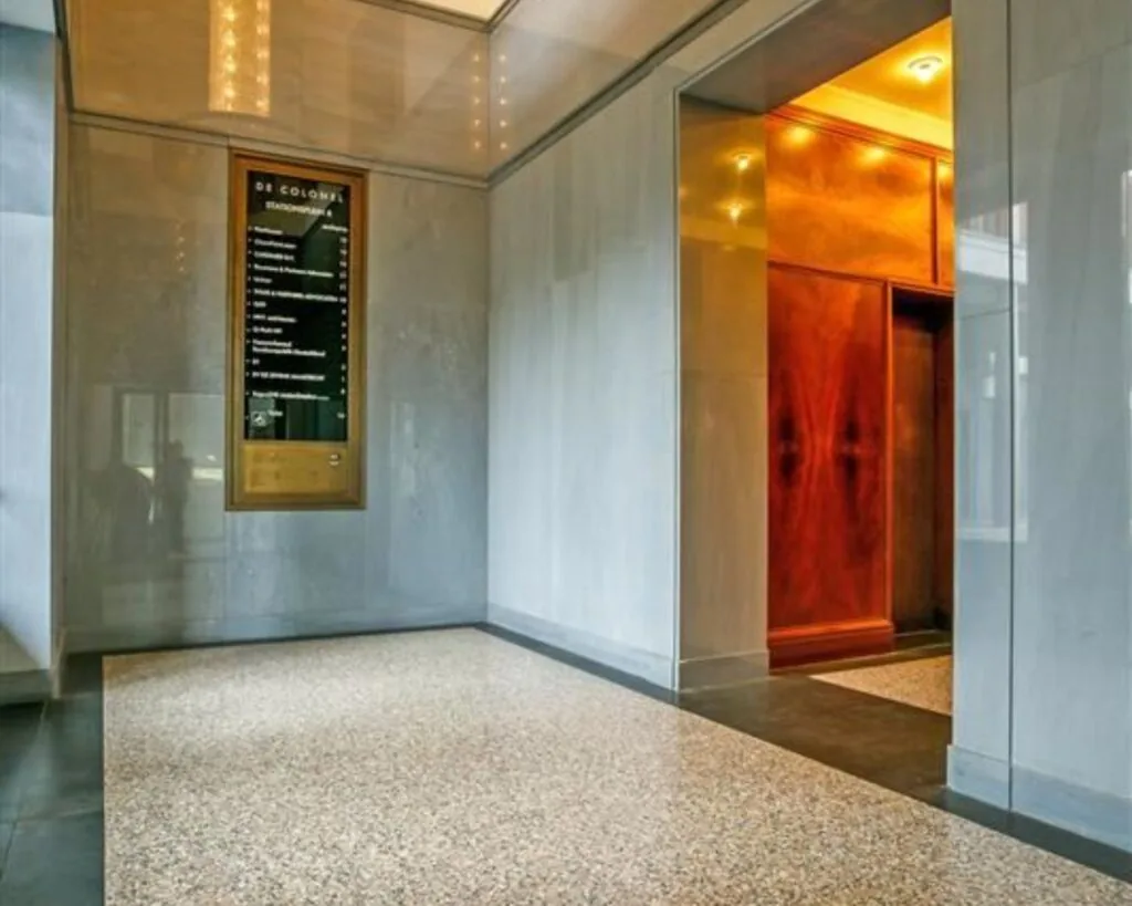 Ingang van een kantoorruimte aan Stationsplein 8 met een lift en een informatiebord van De Colonnes.