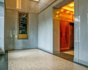 Ingang van een kantoorruimte aan Stationsplein 8 met een lift en een informatiebord van De Colonnes.