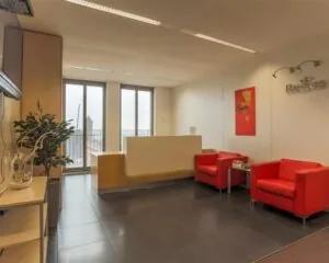 Moderne wachtruimte in een kantoorruimte aan het Stationsplein 8-13 met rode fauteuils, een balie en natuurlijk licht.