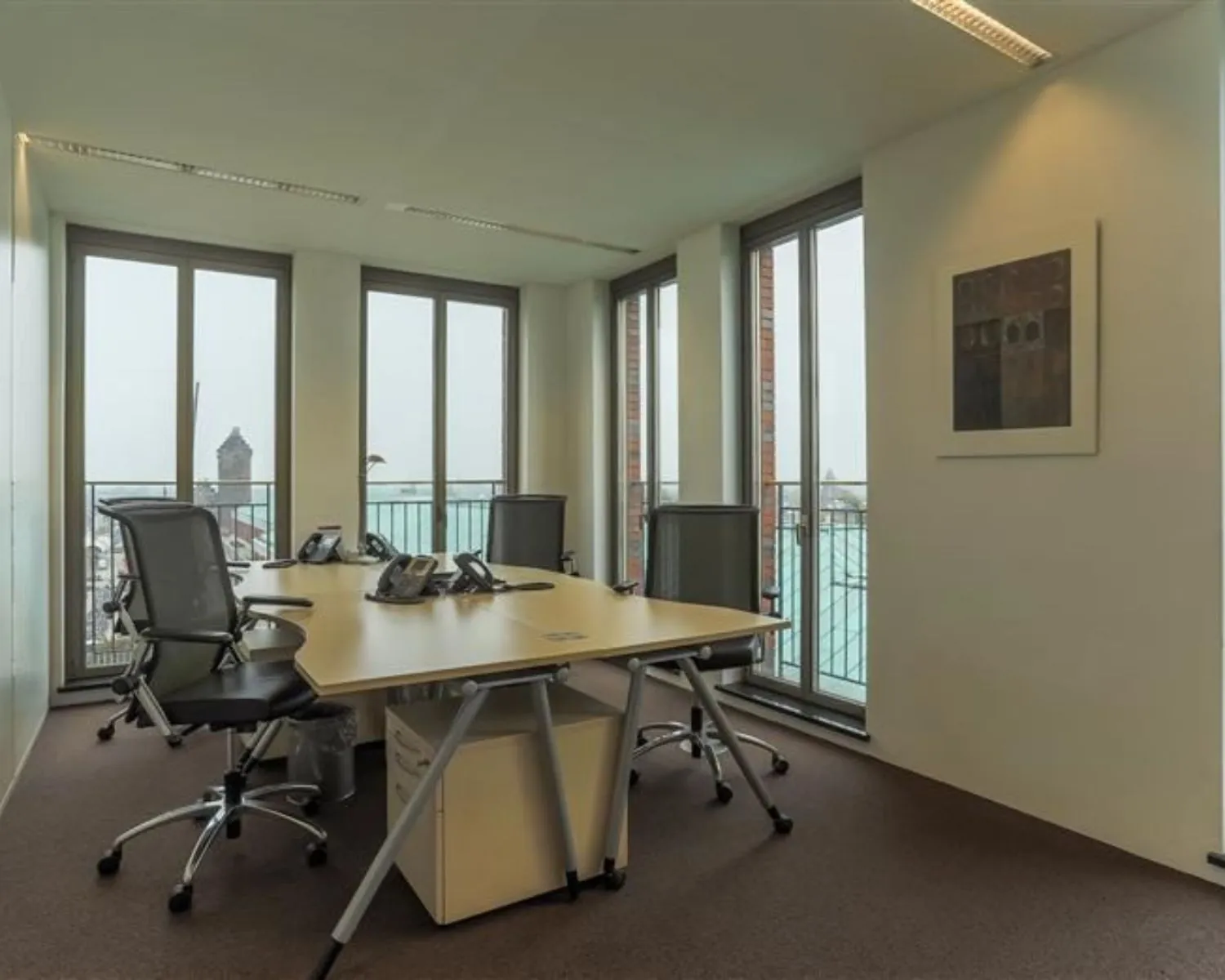 Moderne kantoorruimte te huur aan Stationsplein 8-14 met vergadertafel, bureaustoelen en uitzicht op de stad.