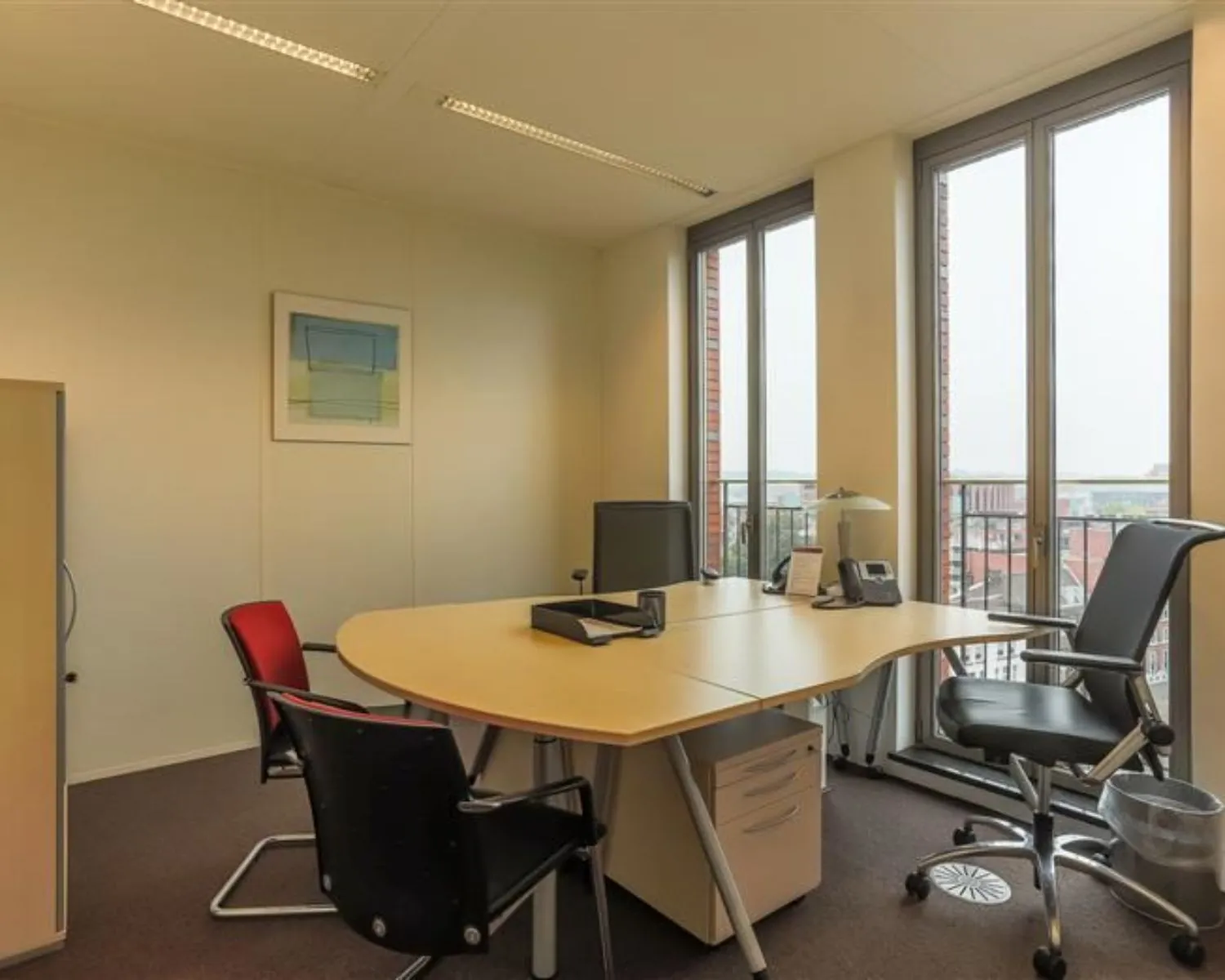 Moderne kantoorruimte te huur aan Stationsplein 8-17 met bureau, stoelen en grote ramen met uitzicht op de stad.