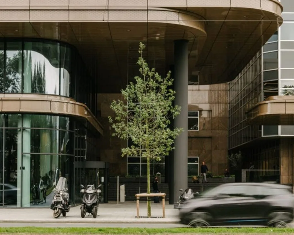 Moderne kantoorruimte aan de Strawinskylaan met glazen gevel, scooters en passerende auto.