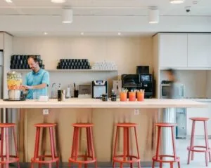 Moderne pantry met rode barkrukken en een drankstation in kantoorruimte aan de Strawinskylaan 4117.